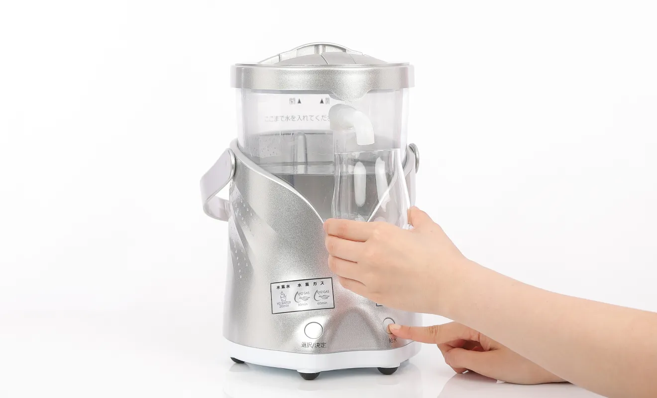 水素飲水器の給水口からグラスに水素水を注ぎ、給水ボタンを押す手元