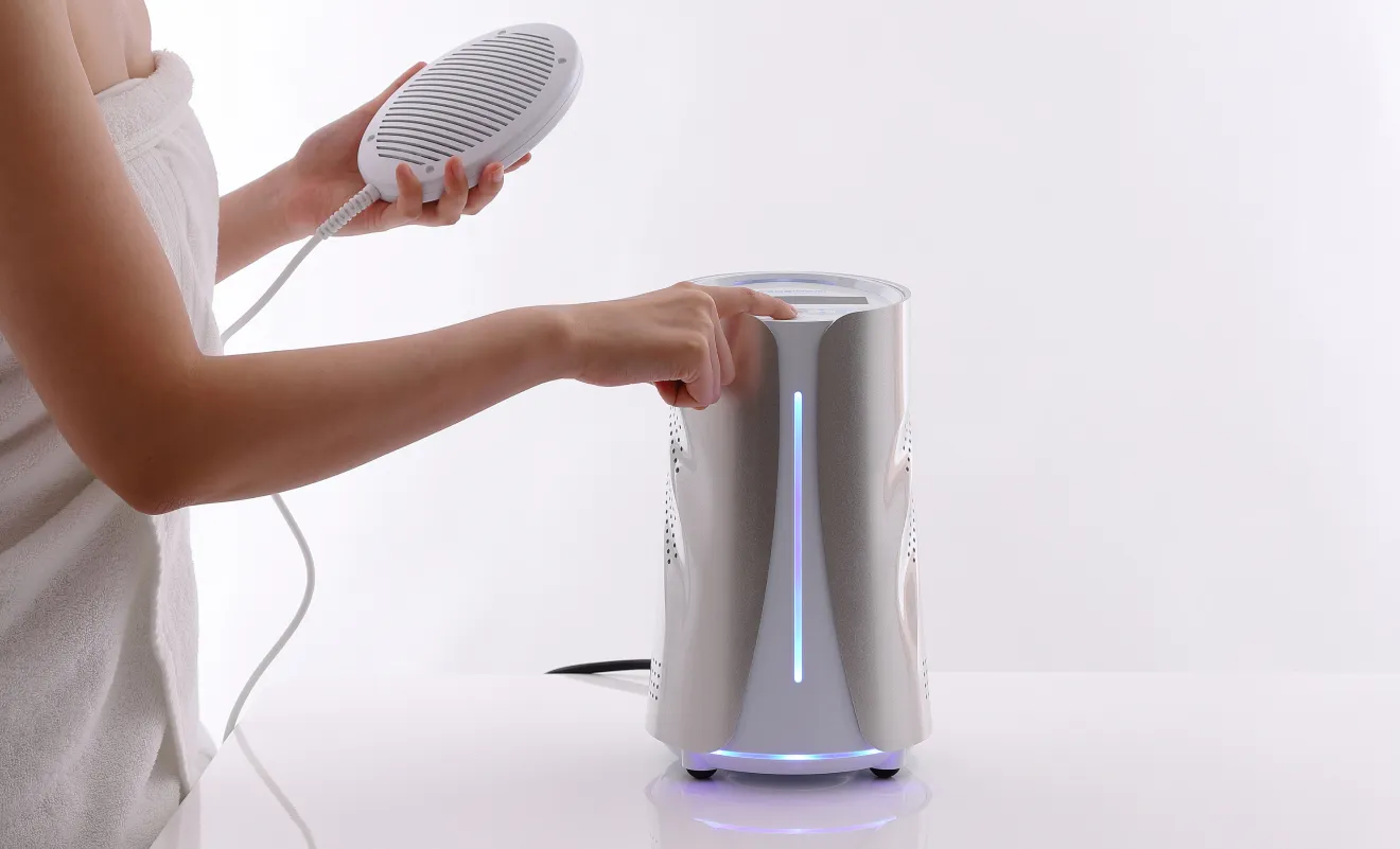 電極を持ち、水素温浴器のスイッチを操作する手元